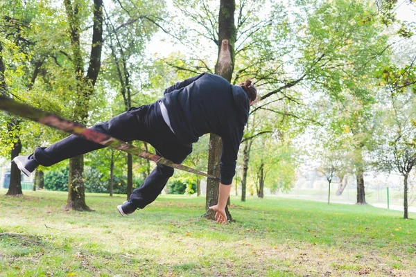 在秋季的城市公园里 男人平衡一 Slackline 的绳索或户外运动 — 图库照片