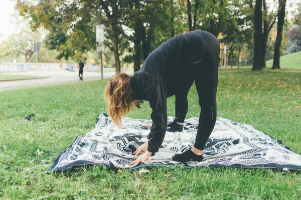 Genç kadın atlet açık bir parkta germe