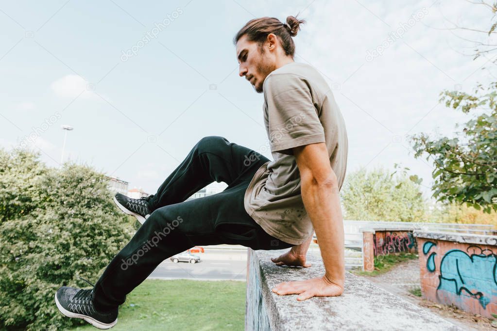 Young beautiful caucasian man doing parkour outdoor in the city in autumn 