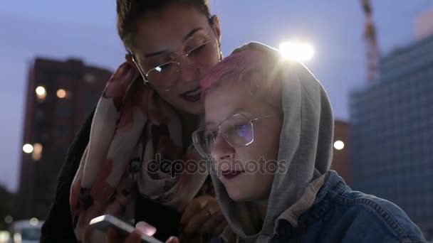 4K超级Hd两名在户外使用智能手机的年轻女性在屏幕上闪烁着光芒 青少年文化 互联网概念 — 图库视频影像