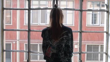 Ağır çekimde genç bir kadın pencereyi açar ve kollarını uzatır. Huzurlu, rahat bir konsept.
