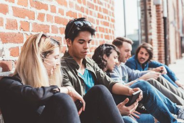 Arkadaşlar multiethncit oturan smartphone kullanarak açık grubu