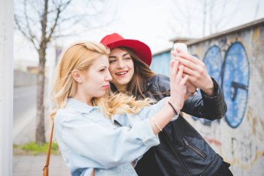 Genç güzel sarışın ve esmer kızlar selfie smartphone ile alarak City eğleniyor 
