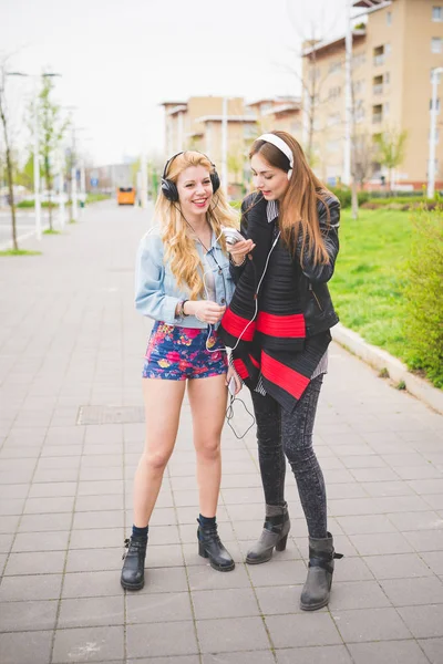 Två Unga Blondin Och Brunett Tjejer Lyssnar Musik Staden Att — Stockfoto