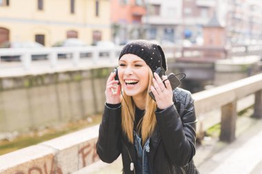 Genç kadın portre güzel sarışın smartphone ile müzik dinleme yürüyüş açık 