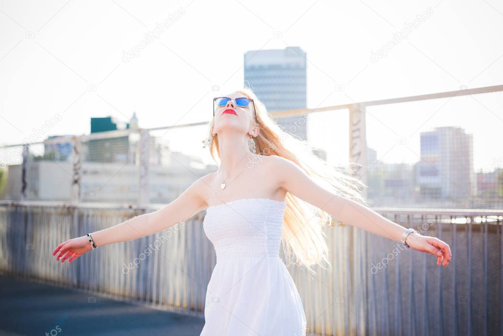 Young beautiful woman in the city spreading arms feeling free 