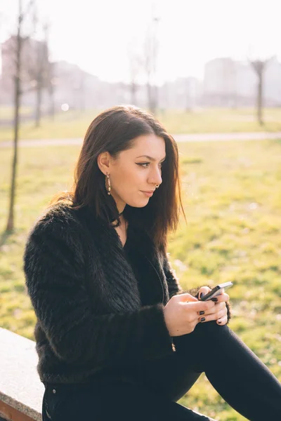 Νεαρή Όμορφη Γυναίκα Εξωτερική Κοιτάζοντας Μακριά Χρησιμοποιώντας Smartphone — Φωτογραφία Αρχείου