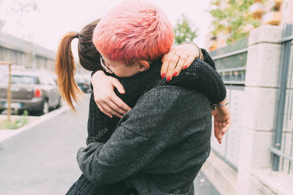 two young women outdoors hugging having fun - affectionate, bonding, interaction concept