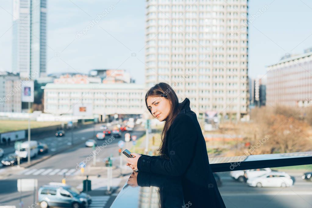 young businesswoman in the city using smartphone looking away 
