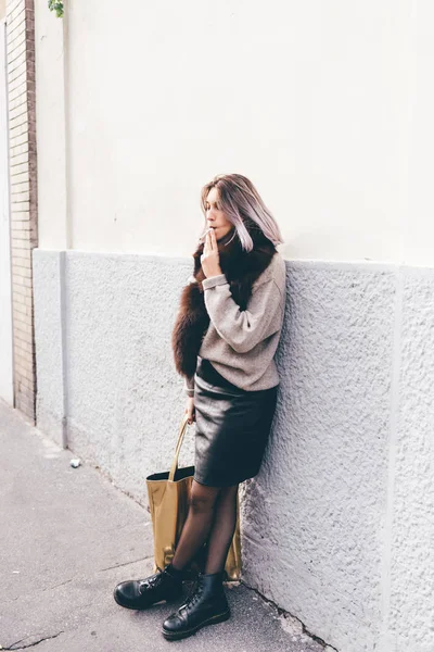 タバコを吸う壁にもたれて市屋外若い美しい白人紫灰色髪の女性 — ストック写真