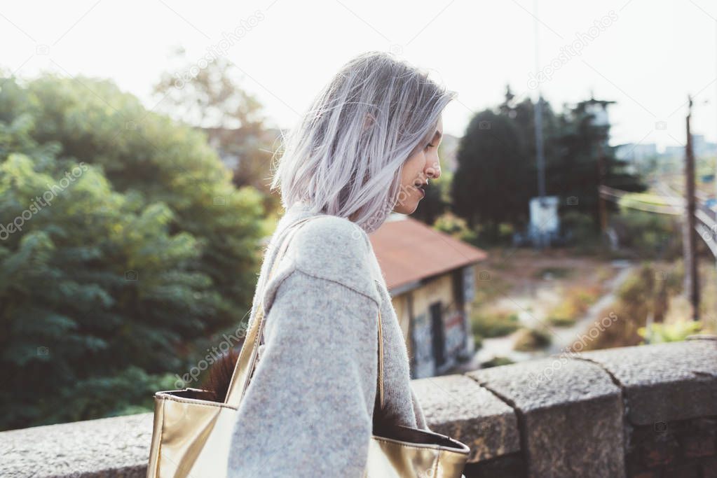 Waist up of young caucasian purple grey hair woman outdoor in the city looking over, smiling