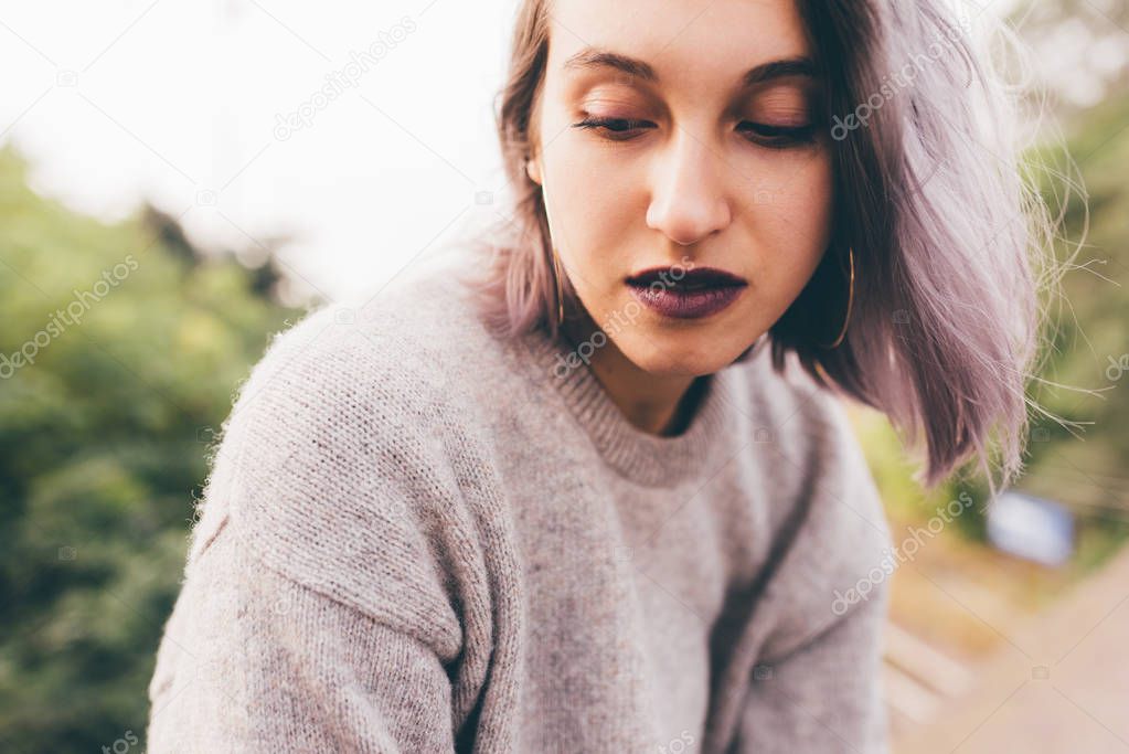 Portrait of young caucasian purple grey hair woman outdoor in the city looking over, smiling 