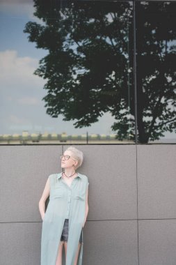 Genç kadın uzağa bakarak duvara yaslanmış ciddi