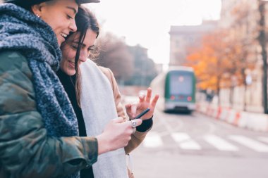 İki kadın lezbiyen çift akıllı telefon kullanıyor - teknoloji, mutluluk, sosyal ağ konsepti