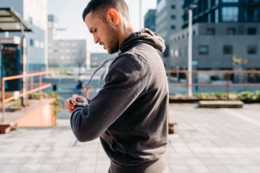 Genç adam spor saati kullanarak dışarıda esniyor. Hazırlık, kullanılabilir teknoloji, sağlıklı yaşam tarzı kavramı.