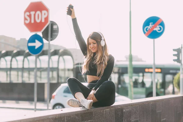 Jovem Mulher Sentada Livre Ouvir Música Segurando Smartphone — Fotografia de Stock