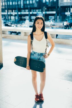 Genç kadın kamera gülümseyen seyir açık tutarak kaykay poz 