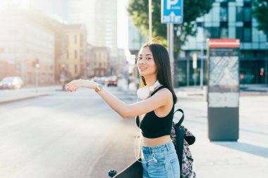 Otostop şehirde açık yürüyen genç Asya uzun kahverengi düz saçlı kadın