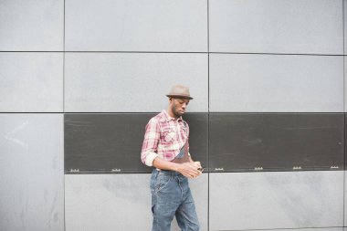 Genç yakışıklı Afrika adam duvarın yanında Smartphone kullanarak 
