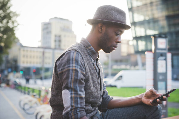 молодой красивый африканский мужчина, использующий смартфон в городе
