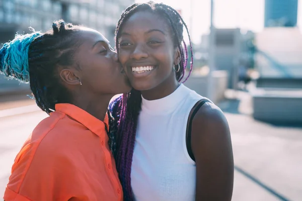 Due donne sorelle all'aperto sorridente baci su il cheeck — Foto Stock