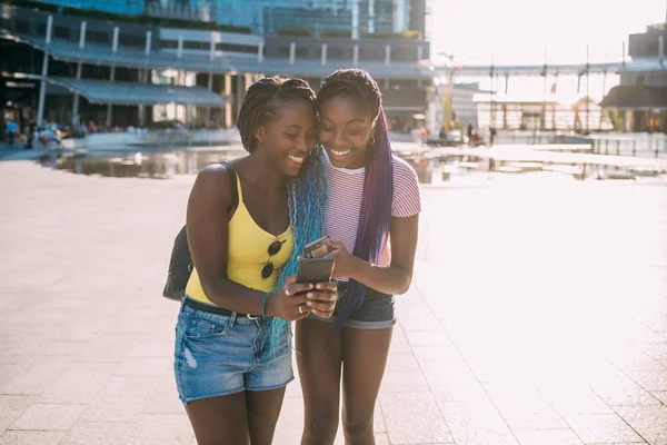 Two young beautiful black sisters outdoor using smartphone — 스톡 사진