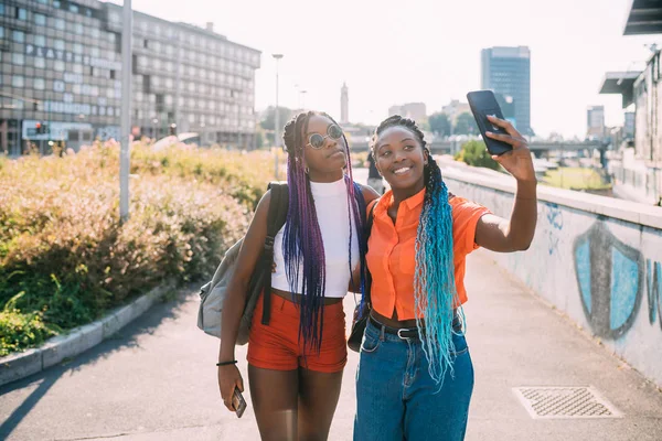 Молоді красиві чорні сестри підсвічування на відкритому повітрі за допомогою смартфона — стокове фото