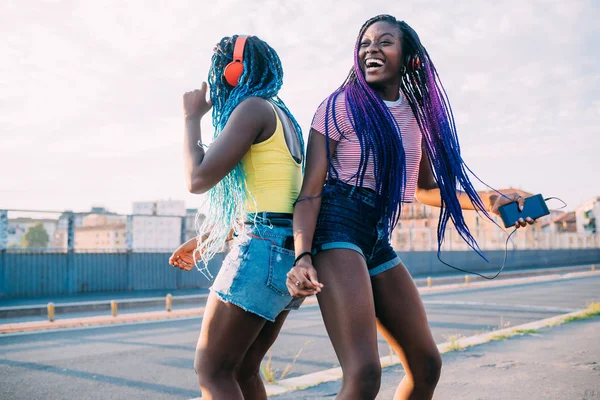 Two women sisters outdoor listening music dancing — ストック写真