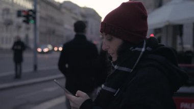 Akşam karanlığında dışarıda sigara içen yetişkin bir kadın akıllı telefon kullanıyor sağlıksız, bağımlı, dalgın bir konsept.