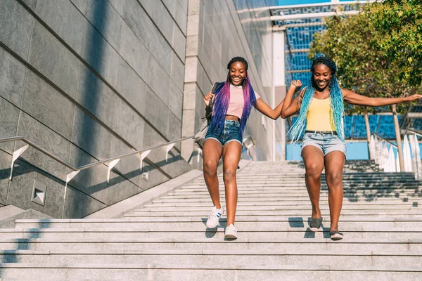 Two beautiful young black sisters walking downstairs together holding hands — 스톡 사진