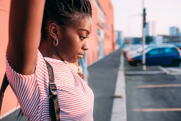 Wanita hitam cantik muda sendirian di luar ruangan cahaya latar belakang termenung menyentuh rambut — Stok Foto