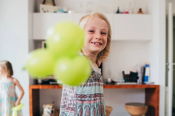 Young beautiful female child indoor at home playing with balloon looking camera smiling — 스톡 사진