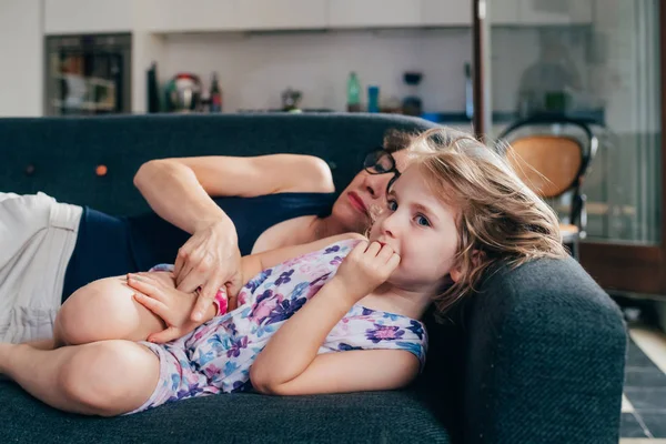 Mother with female child indoor on the couch cuddling — 스톡 사진