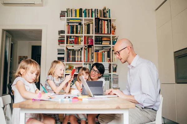 Parents indoor sitting table homeschooling with three female children — Stock Photo, Image