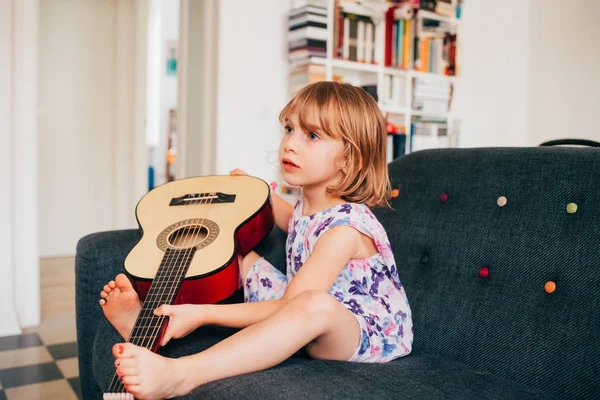 女性子供屋内で家庭用ギターを保持 — ストック写真