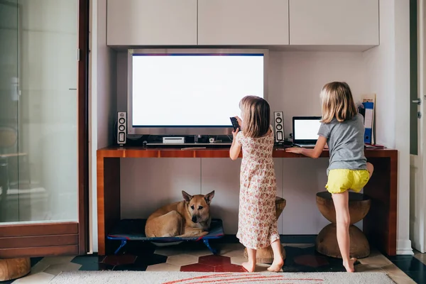 Duas crianças do sexo feminino assistindo televisão e computador muito perto — Fotografia de Stock
