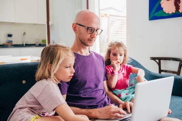 Πατέρας βλέποντας streaming κινούμενα σχέδια στον υπολογιστή με δύο κόρες — Φωτογραφία Αρχείου