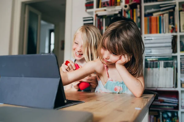 Two little sisters indoor at home using tablet sitting table — Stock Photo, Image