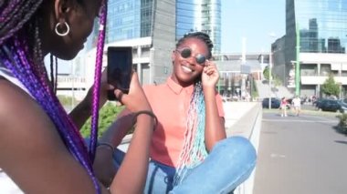 İki kız kardeş dışarıda akıllı telefon kullanarak fotoğraf çekiyorlar. Teknoloji, paylaşım konsepti.