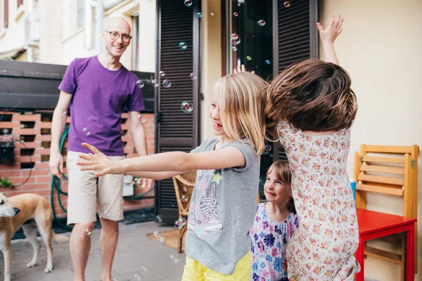 Father and two female children outdoor playing bubble soap — 스톡 사진