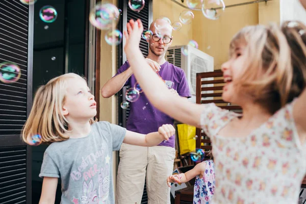 Father and two female children outdoor playing bubble soap — 스톡 사진