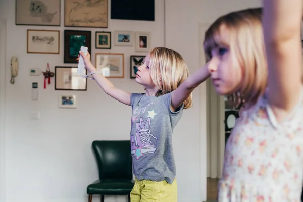 Evde elinde joystick tutan iki kız çocuk video oyunu oynuyor. — Stok fotoğraf