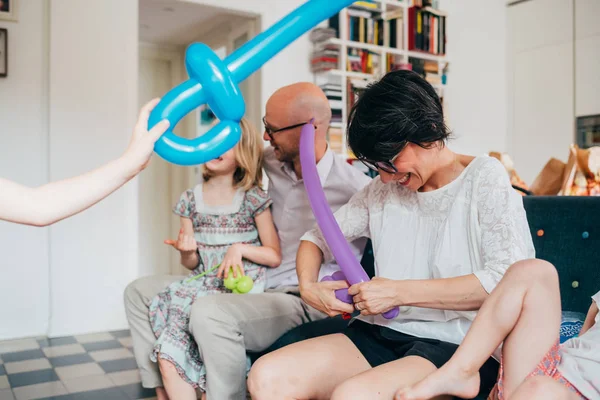 Family indoor sitting couch playing with balloon toys — 스톡 사진