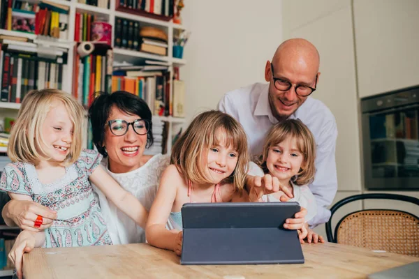 Three little sisters indoor at home using tablet sitting table s — Stock Photo, Image