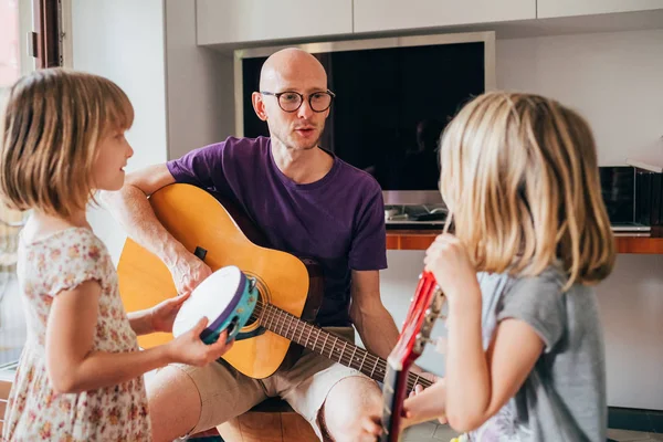 父は娘たちにギターの弾き方や演奏法を教え — ストック写真