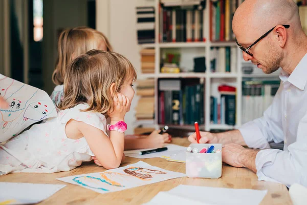 Padre de dos niñas dibujando en un interior de papel en casa — Foto de Stock
