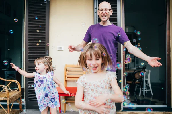 Father and two female children outdoor playing bubble soap — 스톡 사진