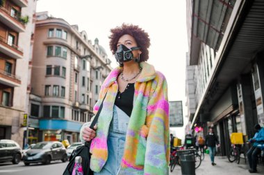 Milano 'da dışarıda yürüyen genç bir kadın sağlık maskesi takıyor. Kirlilik ve virüsten korunuyor. Anti-duman, enfeksiyon, koruma konsepti.