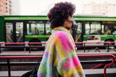 Milano 'da dışarıda yürüyen genç bir kadın sağlık maskesi takıyor. Kirlilik ve virüsten korunuyor. Anti-duman, enfeksiyon, koruma konsepti.