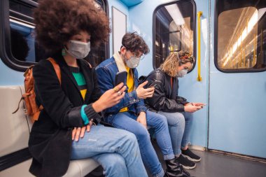 Metroda kirlilikten ve virüsten korunmak için akıllı telefon kullanan üç çok ırklı arkadaş. Sis önleyici, enfeksiyon, protestocu konsepti.